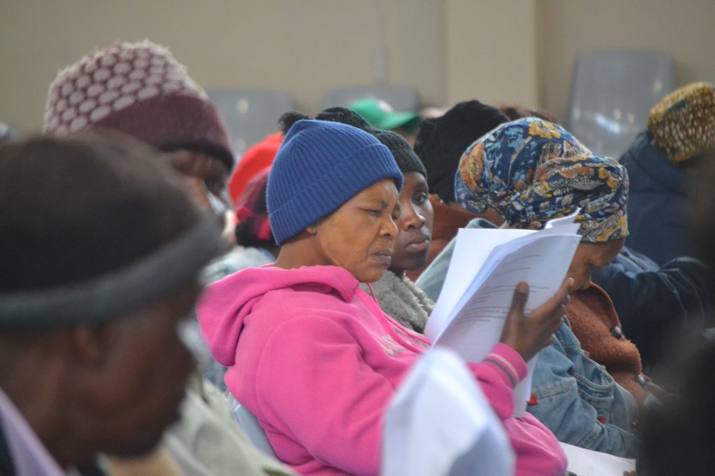 A woman sits frowning while reading the NHI Bill