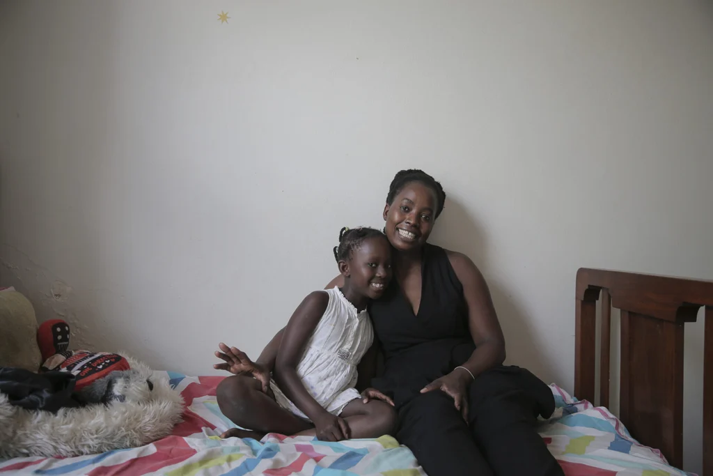 Primrose Modisane sitting on a bed with her youngest daughter Ayanda.